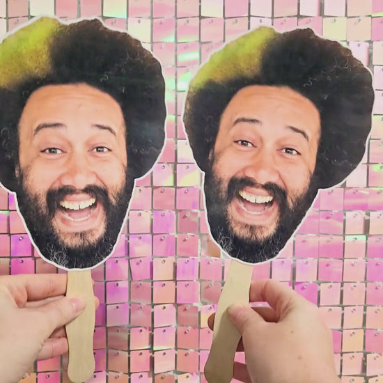 Two face fans being held and moved back and forth depicting person's face